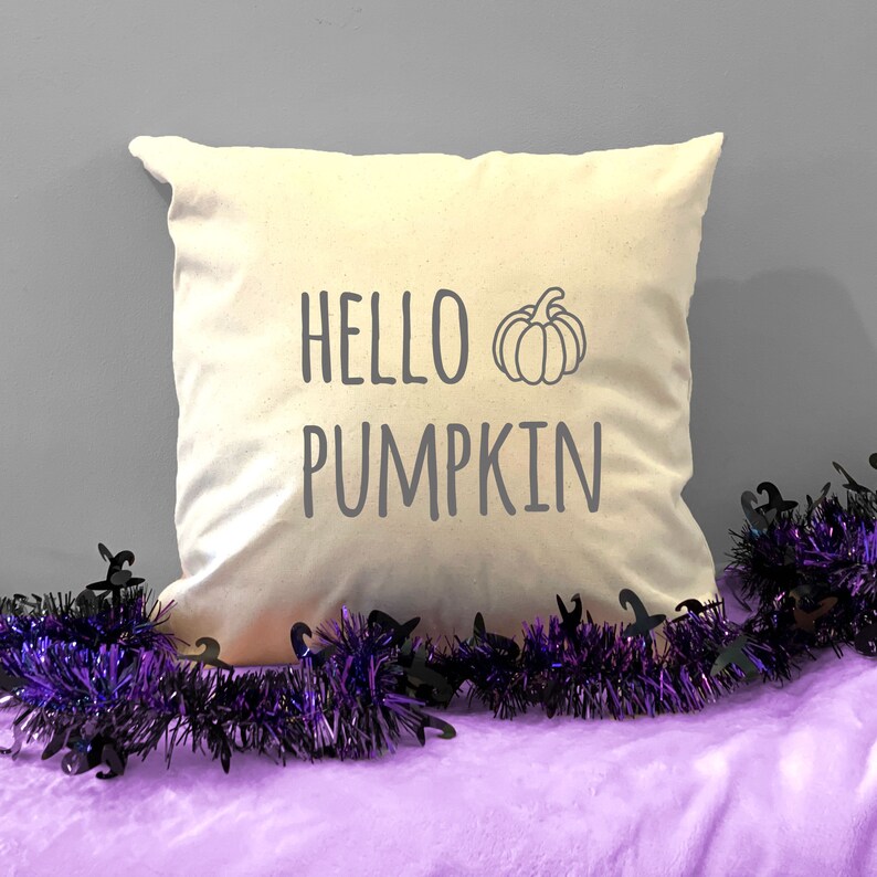 May include: A white throw pillow with the text "HELLO PUMPKIN" and a simple line drawing of a pumpkin in gray.