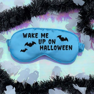 May include: A light blue sleep mask with the text "Wake Me Up On Halloween" and black bat silhouettes.
