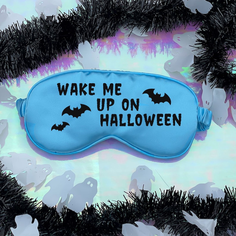 May include: A light blue sleep mask with the text "Wake Me Up On Halloween" and black bat silhouettes.