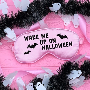May include: Pink satin sleep mask with the text "Wake Me Up On Halloween" and black bat silhouettes.