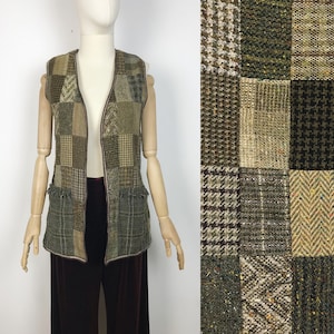 May include: A brown and green patchwork vest with a V-neck and fringe detail. The vest is made of different types of tweed fabric.