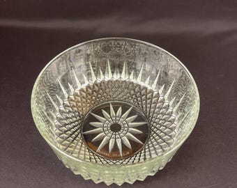 May include: Clear glass bowl with a starburst design on the base and diamond pattern on the sides. The bowl has a scalloped edge and is made of clear glass. The bowl is likely vintage and suitable for serving.