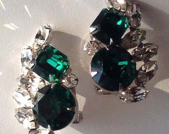 May include: A pair of clip-on earrings with a cluster of clear rhinestones and three emerald green stones.