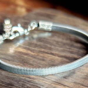 Può includere: Un braccialetto espandibile in argento con un design testurizzato e rigato. Il braccialetto ha una chiusura a scatto.