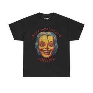 May include: Black t-shirt with a graphic of a cracked doll face with the text "Dead Dolls Society Since 1976" printed on the front.