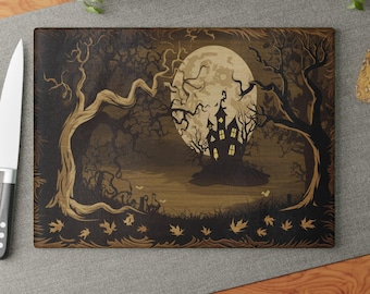 May include: A wooden cutting board with a spooky Halloween design. The board features a dark forest scene with a haunted house, a full moon, and scattered leaves.