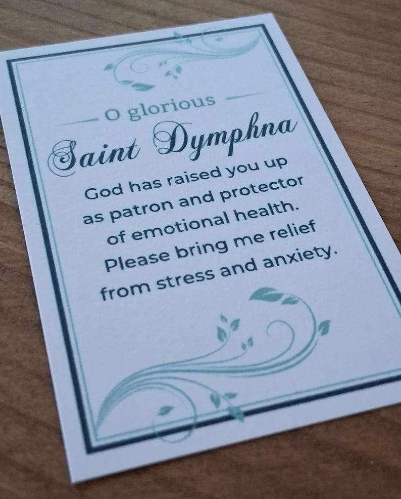 May include: A rectangular prayer card featuring a white background with a light blue border and decorative leaf flourishes. The text reads: O glorious Saint Dymphna, God has raised you up as patron and protector of emotional health. Please bring me relief from stress and anxiety.