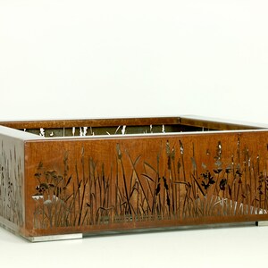 Pu&ograve; includere: Un vaso quadrato in metallo arrugginito con un design a taglio di erbe alte e fiori selvatici. Il vaso ha un design moderno e minimalista e sarebbe un'ottima aggiunta a qualsiasi giardino o patio.