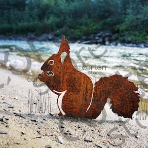 Könnte beinhalten: Rostige Metall-Silhouette eines Eichhörnchens steht an einem Sandstrand mit Fluss im Hintergrund. Das Eichhörnchen ist im Profil, der Schwanz ist aufgerollt. Natürliches, Outdoor-Thema.