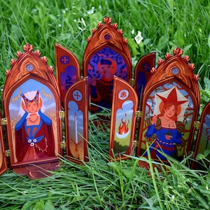 May include: A collection of decorative wooden panels with arched tops, depicting illustrations of figures in medieval clothing. The panels are mainly brown with gold detailing, set against a backdrop of green grass.