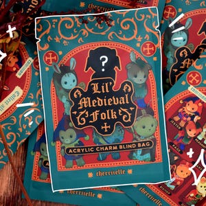 May include: A teal blind bag with the text "Lil' Medieval Folk" and illustrations of cartoon characters. The bag also features the text "Acrylic Charm Blind Bag" and the brand name "cherriuelle". Other bags are visible in the background.