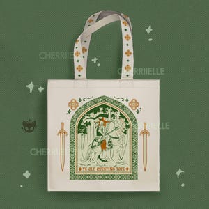 May include: A cream-colored canvas tote bag featuring a green and orange graphic of a knight on horseback within an arched frame. The design includes two swords on the sides and the text "YE OLD QUESTING TOTE" at the bottom. The handles have a repeating cross pattern.