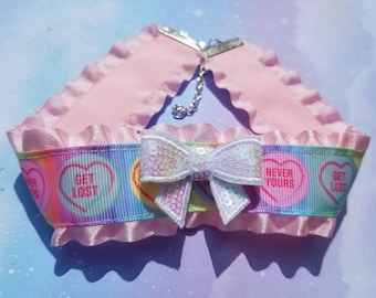 May include: Pink choker with a white bow and rainbow ribbon featuring candy hearts with the text "Get Lost" and "Never Yours".