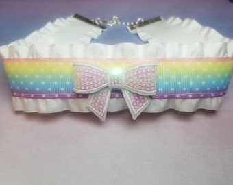 May include: White choker with a rainbow ribbon and a sparkly pink bow. The ribbon has white polka dots.
