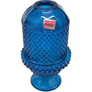 Puede incluir: Una taza de cerámica blanca con un asa negra y el texto "But First, Coffee" en negro, con una fuente de estilo manuscrito. La taza está sobre una superficie blanca.