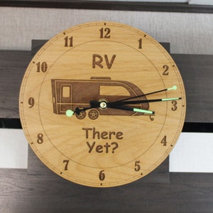 May include: A wooden clock with a camper van design and the text "RV There Yet?" The clock face has black hands and green accents.