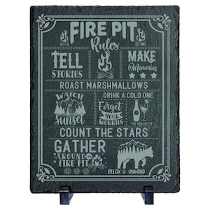 May include: Black slate sign with white text that reads "Fire Pit Rules". The rules include "Tell Stories", "Make Memories", "Roast Marshmallows", "Drink a Cold One", "Forget Your Worries", "Count the Stars", "Gather Around the Fire Pit", and "Relax & Unwind".