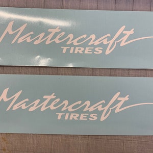 May include: Two white vinyl decals with the words "Mastercraft TIRES" in a cursive font. The decals are rectangular and have a light blue background. The decals are likely for a vehicle.