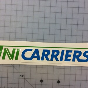 May include: A white sticker with the text "UNICARRIERS" in green and blue lettering. The word "UNI" is in green and the word "CARRIERS" is in blue.