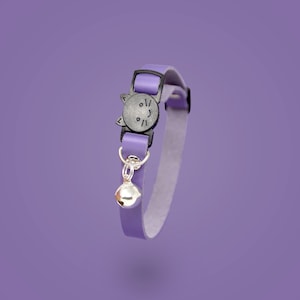 May include: A purple cat collar with a black cat face buckle and a silver bell.