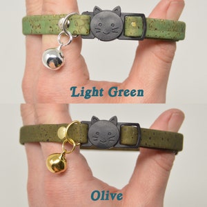 K&ouml;nnte beinhalten: Zwei Katzenhalsb&auml;nder aus Korkmaterial mit einer katzenf&ouml;rmigen Schnalle. Das obere Halsband ist hellgr&uuml;n und das untere Halsband ist olivgr&uuml;n. Beide Halsb&auml;nder haben eine kleine Glocke.