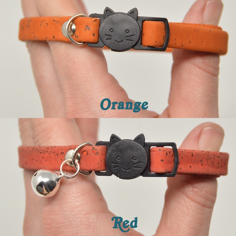 K&ouml;nnte beinhalten: Zwei Katzenhalsb&auml;nder aus Kork mit einer schwarzen Katzenkopf-Schnalle. Das obere Halsband ist orange und das untere Halsband ist rot. Das rote Halsband hat eine silberne Glocke.