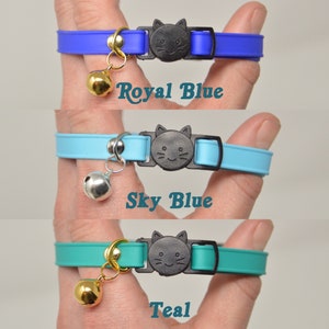 May include: Three cat collars in different colors: royal blue, sky blue, and teal. Each collar has a black cat charm with a smiling face and a bell.
