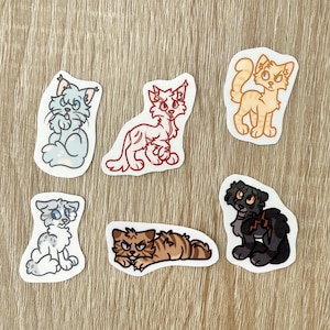 May include: A collection of seven cat stickers in various colors and poses. The stickers feature cartoon-style illustrations of cats in shades of gray, red, orange, brown, and black. Each sticker is outlined in white and has a unique design.