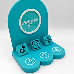 May include: A teal social media display stand with the word "swypes" in a white circle. It features icons for TikTok, Instagram, and a website, along with contactless payment symbols. The stand is designed to promote social media presence.