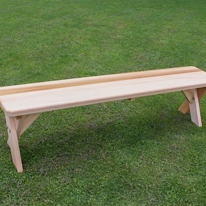 May include: A wooden bench with a natural finish. The bench has a single, wide, horizontal slat across the top, creating a two-toned effect. The bench is made of cedar wood and is suitable for outdoor use.