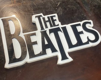 May include: White 3D sign with black lettering that reads "The Beatles".