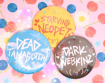 May include: Three round buttons with colorful backgrounds and white text. The first button is blue with white text that says "DEAD TAMAGOTCHI". The second button is yellow with red text that says "STARVING NEOPET". The third button is black with white text that says "DARK WEBKINZ".