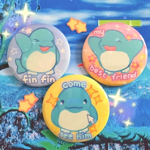 May include: Three colorful round buttons with cartoon blue penguins. The buttons have different text on them: "fin fin", "come see him", and "my best friend".