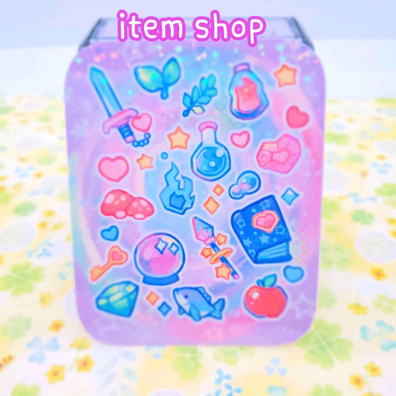 May include: A holographic sticker sheet with a variety of cute, colorful illustrations, including a sword, potion bottles, stars, a crystal ball, a book, and an apple. The sheet is on a purple background with a swirling pattern.