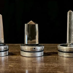 K&ouml;nnte beinhalten: F&uuml;nf klare Quarzkristallspitzen auf Metallsockeln. Die Kristalle sind in verschiedenen Formen und Gr&ouml;&szlig;en. Die Sockel sind silberfarben und haben ein dekoratives Design.