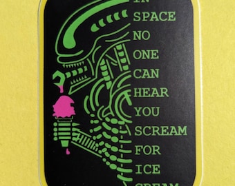May include: A black sticker with a neon green alien design holding a pink ice cream cone. The text reads "IN SPACE NO ONE CAN HEAR YOU SCREAM FOR ICE CREAM" in green. The sticker has a yellow border.