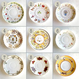May include: Nine decorative ceramic saucers with various designs. The saucers feature floral, zodiac, and whimsical illustrations. Colors include white, gold, yellow, and red. Some have scalloped edges and gold trim. A collection of vintage teacup saucers.