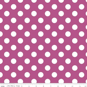 May include: A fabric with a repeating pattern of large white polka dots on a magenta background. The image includes a ruler along the bottom edge, with measurements in inches.