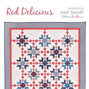 May include: A red, white, and blue quilt with a star pattern. The quilt is called "Red Delicious" and is a pattern by Amy Smart. The quilt is displayed on a white wall with a red chair in front of it.