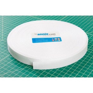 May include: A white nylon webbing strap rolled up on a green cutting mat. The strap is 1 inch wide and is labeled "annie.com".