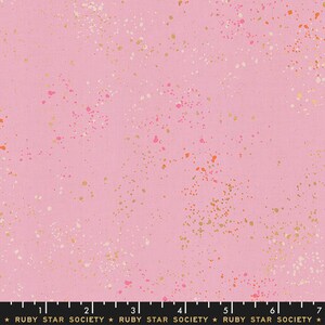 May include: Pink fabric with a speckled pattern of gold, white, and pink dots. The fabric has a ruler with the text "RUBY STAR SOCIETY" printed on it.