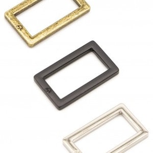 May include: Three metal rectangular rings in gold, black, and silver.