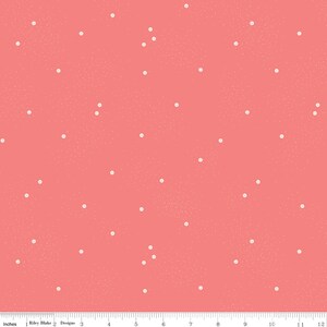 May include: Coral fabric with a scattered dot pattern. The dots are small and white, creating a subtle contrast against the solid background. The fabric has a textured appearance, and the image includes an inch ruler along the bottom.