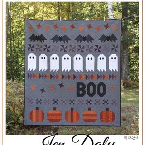 May include: A Halloween-themed quilt with a gray background, featuring bats, ghosts, pumpkins, and the word "BOO." The quilt is designed by Jen Daly Quilts and is displayed outdoors, showcasing a festive autumn design.