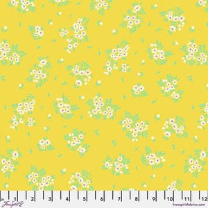 May include: Yellow fabric with a repeating pattern of small white flowers with red centers and light green leaves. The floral design is scattered across the fabric. The fabric has a ruler along the bottom edge.