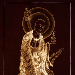 Puede incluir: Una pintura dorada de una deidad budista de pie sobre una flor de loto. La deidad sostiene un bastón y una llama en sus manos. La pintura está sobre un fondo oscuro.