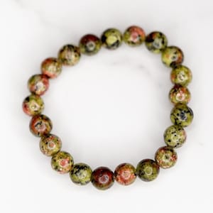 May include: A green, red and black speckled stone bracelet with round beads.
