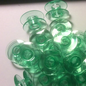 Puede incluir: Un montón de 20 bobinas de plástico verde para una máquina de coser.