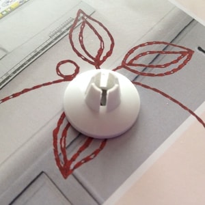 May include: White plastic sewing machine foot with a small opening in the center. The foot is designed to be used with a sewing machine.
