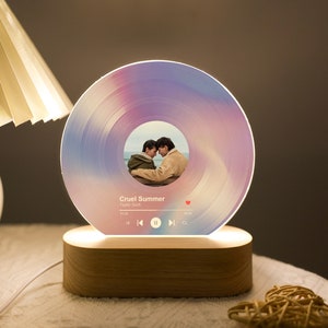 May include: A wooden base with a circular light-up record-shaped lamp. The lamp features a photo of two people and the song title "Cruel Summer" by Taylor Swift.